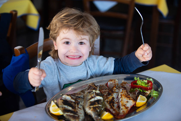 Vakantie aan zee. Lunch op zee. Lunch op een cruise. Het kind eet zeevissen als avondeten. Gezond voedsel voor kinderen. - Foto, afbeelding