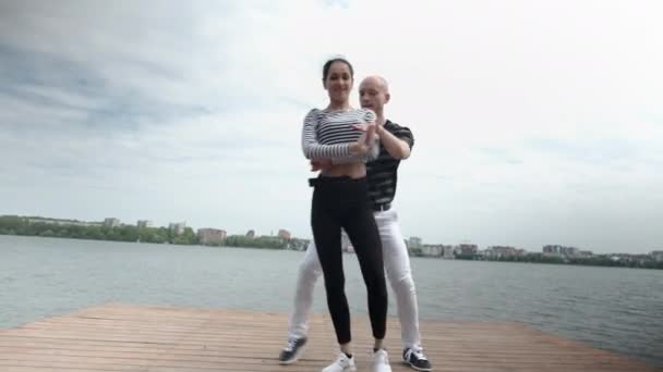 The couple in love dance social dance bachata pier on the lake, town horizon - Felvétel, videó