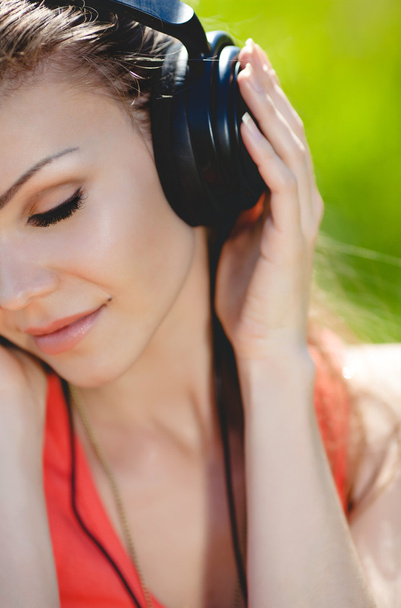 Beautiful young woman listen to music wearing headphones outdoors - 写真・画像