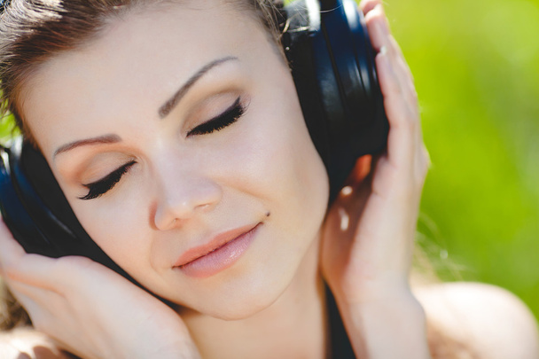 schöne junge Frau hört Musik mit Kopfhörern im Freien - Foto, Bild