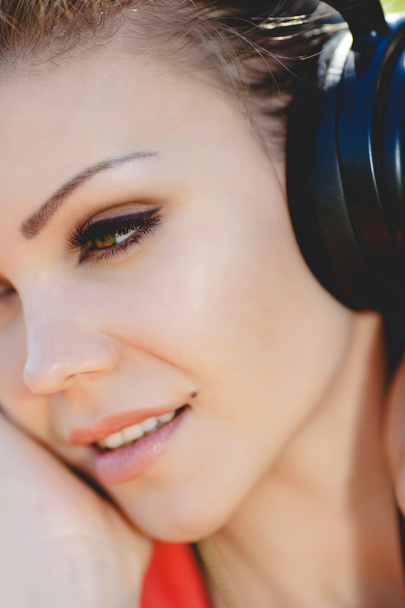 Beautiful young woman listen to music wearing headphones outdoors - Photo, Image