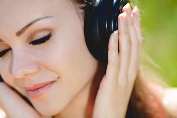 Beautiful young woman listen to music wearing headphones outdoors - Foto, Bild