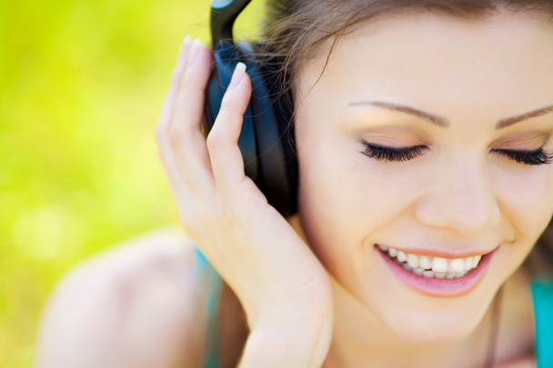 Beautiful young woman listen to music wearing headphones outdoors - 写真・画像