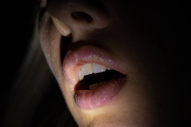 un visage féminin dans l'obscurité illuminé par une lanterne
 - Photo, image