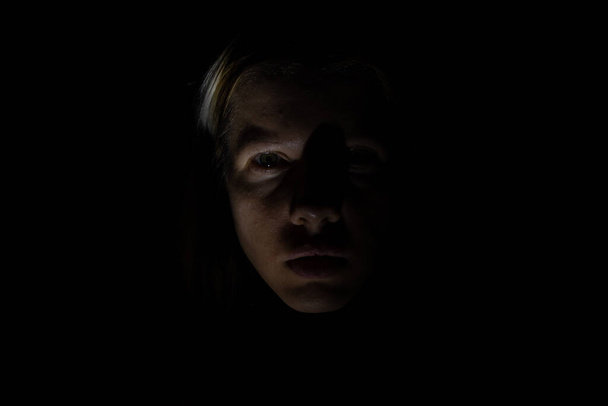 ένα γυναικείο πρόσωπο στο σκοτάδι φωτισμένο από ένα φανάρι - Φωτογραφία, εικόνα