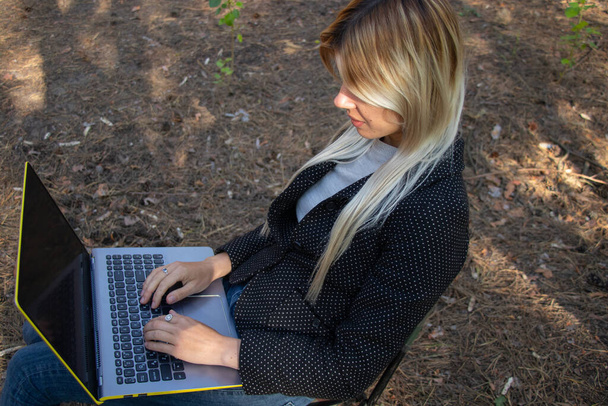 Ukrajinská dívka sedí s laptopem v karanténním jehličnatém lese - Fotografie, Obrázek