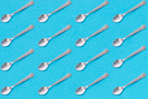 Metal dessert spoons with blue background. Repeat pattern. - Photo, Image