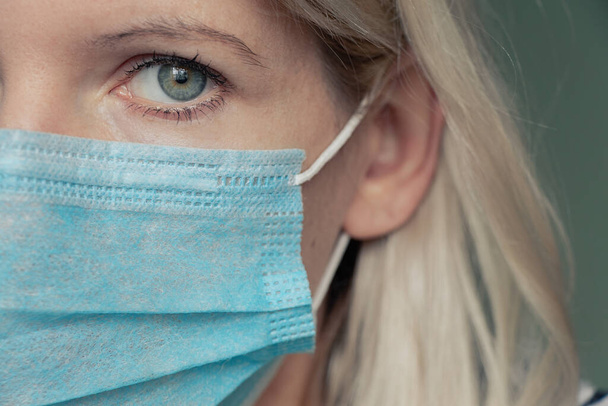 egy fiatal ukrán nő orvosi maszkban az arcán a 2020-as otthoni karantén világjárvány idején - Fotó, kép