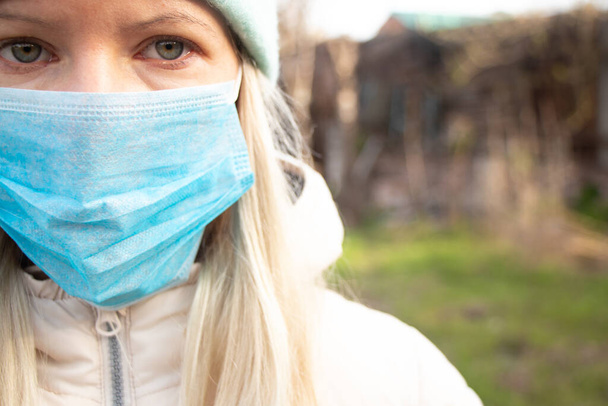 mladá dívka v zimním oblečení a lékařská maska na ulici na slunný den - Fotografie, Obrázek