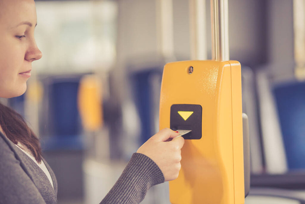 Νεαρή γυναίκα χέρι εισάγει το εισιτήριο του λεωφορείου στον επικυρωτή, επικύρωση και τικ τακ, έννοια των μέσων μαζικής μεταφοράς  - Φωτογραφία, εικόνα