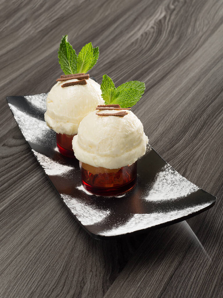 Deux glaces à la vanille avec une décoration élégante sur une surface en bois neutre
 - Photo, image
