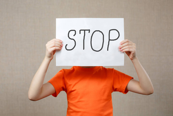 Little girl holding a piece of paper with the word STOP in front of her - Photo, image