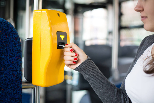 Νεαρή γυναίκα χέρι εισάγει το εισιτήριο του λεωφορείου στον επικυρωτή, επικύρωση και τικ τακ, έννοια των μέσων μαζικής μεταφοράς  - Φωτογραφία, εικόνα