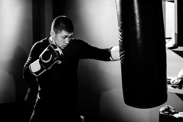 Egy koncentrált profi bokszoló megüt egy boxzsákot.. - Fotó, kép
