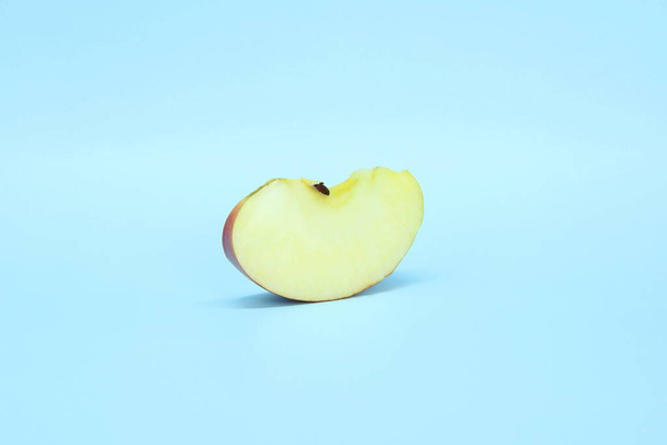 Slice a juicy fresh apple on a blue background. Delicious sliced fruit - Foto, imagen