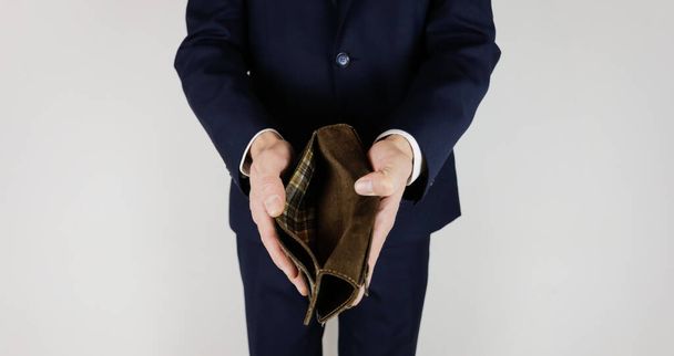 Takım elbiseli bir adam elinde parasız boş bir cüzdan tutuyor. Finansal kriz. İflas, iş dünyasında. İşveren hayal kırıklığına uğradı.. - Fotoğraf, Görsel
