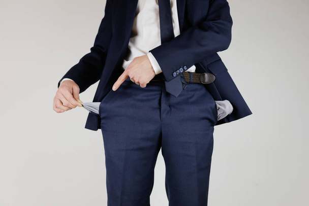 Ένας άντρας με κοστούμι, άδειασε τις τσέπες του. Οικονομική κρίση. Πτώχευση στις επιχειρήσεις. Ένας επιχειρηματίας χωρίς χρήματα. - Φωτογραφία, εικόνα