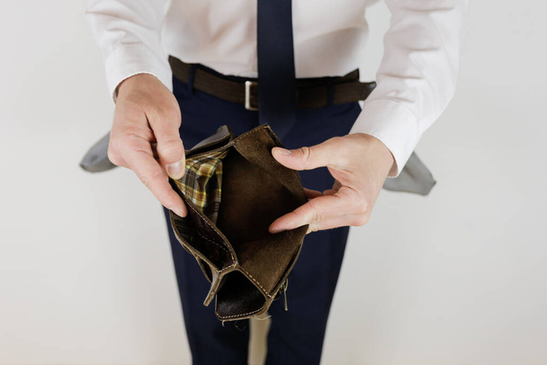 Mężczyzna w garniturze biznesowym trzyma w rękach pusty portfel bez pieniędzy. Kryzys finansowy. Bankructwo w biznesie. Pracodawca jest rozczarowany.. - Zdjęcie, obraz