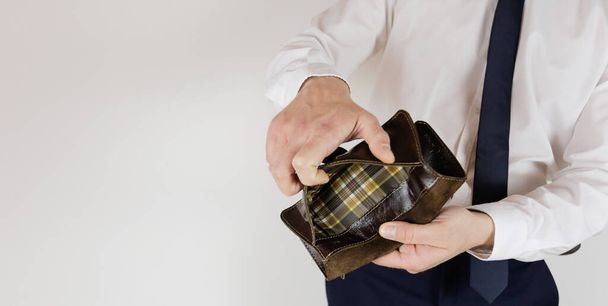 Liikepukuinen mies pitää kädessään tyhjää lompakkoa ilman rahaa. Rahoituskriisi. Konkurssin liike-elämässä. Työnantaja on pettynyt
. - Valokuva, kuva