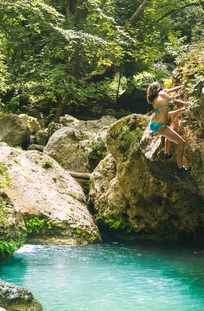 Žena v plavkách šplhá na útes nad vodou, Lezení přes horskou řeku, Bouldering v Turecku, Silný horolezec je trénink na přirozeném terénu, Hluboká voda sólo. - Fotografie, Obrázek