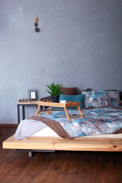 Bedroom interior with a small table on bed and a cup of coffee. Wooden breakfast tray on bed in morning. cup of espresso in morning to bed. Honeymoon, surprise. interior dark bedroom. Room decor loft - Foto, Bild