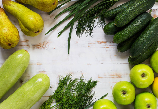 Fresh green vegetables and fruits - pears, zucchini, cucumbers, green onions, dill, parsley, apples on the wooden white background. Concept healthy food photo - Photo, Image