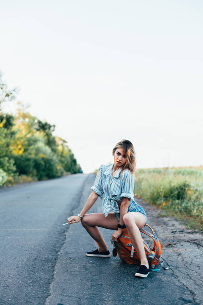 Beautiful girl hitchhiking on the track in a mans shirt - 写真・画像