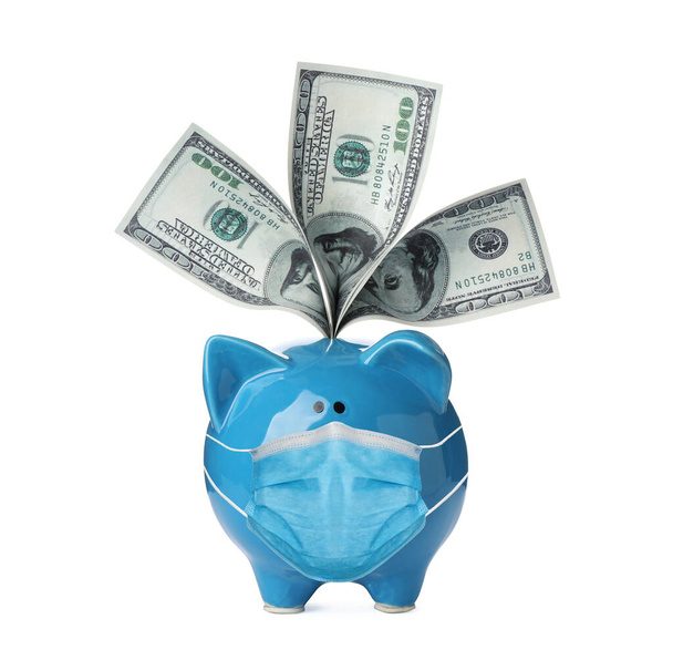 Piggy bank with face mask and money bills isolated on white - 写真・画像