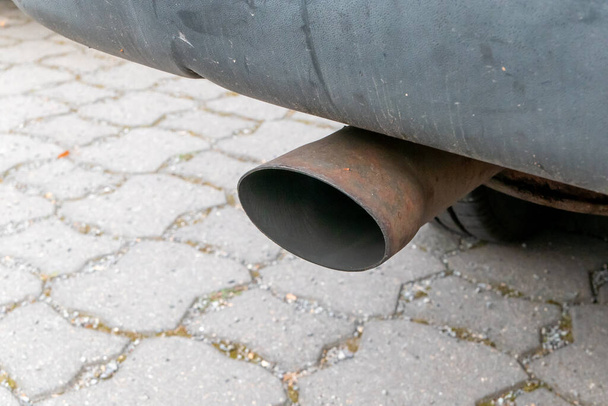 Berlin, Berlin/Germany - 06.08.2019: A car exhaust under a vehicle without smoke or exhaust fumes The tailpipe is sooty and rusted. - Photo, Image