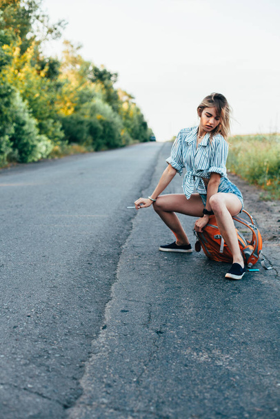 Beautiful girl hitchhiking on the track in a mans shirt - 写真・画像
