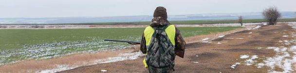 Sazlıklarda güneşe karşı silahlı bir avcının silueti. Köpekli ördekler için bir pusu. - Fotoğraf, Görsel