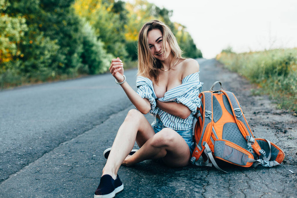 Beautiful girl hitchhiking on the track in a mans shirt - Valokuva, kuva