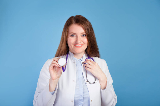 Portrait of confident young woman doctor on blue studio background. - Φωτογραφία, εικόνα