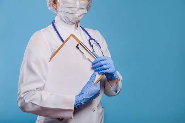 Healthcare worker in surgical sterile protective clothing holding blank placard. Coronovirus concept - Foto, immagini
