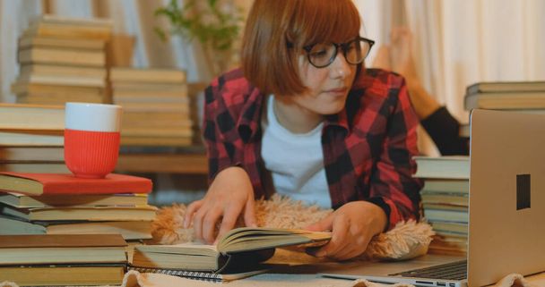 Jeune étudiante étudiant à la maison avec de nombreux livres et ordinateur portable
 - Photo, image