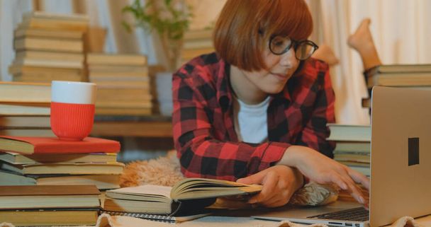 Giovane studentessa che studia a casa con molti libri e laptop
 - Foto, immagini