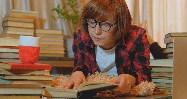 Jonge vrouw student thuis studeren met veel boeken en laptop - Foto, afbeelding
