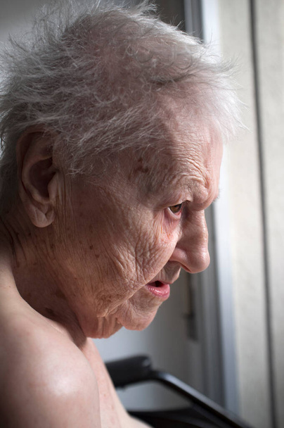 portrét smutné osamělé zamyšlené starší ženy dívající se z okna - Fotografie, Obrázek