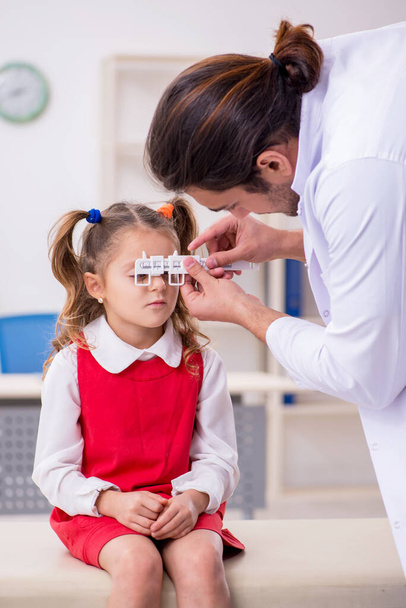 Menina pequena visitando jovem médico oculista masculino - Foto, Imagem
