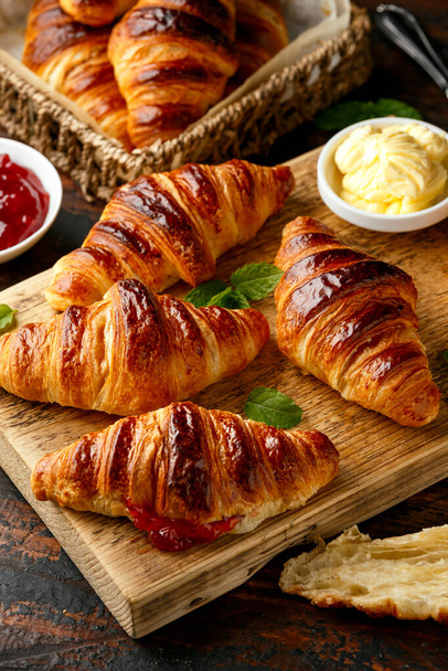 Frisch gebackene Croissants mit Butter, Erdbeermarmelade und Tee zum Frühstück oder Brunch - Foto, Bild