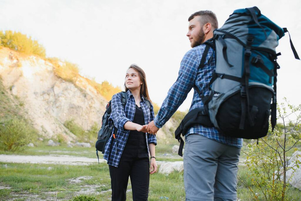 Couple enjoying beautiful views on the mountains, while traveling with backpacks in the mountains during the summer vacations - Photo, Image