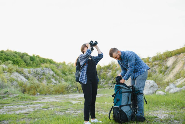 Couple enjoying beautiful views on the mountains, while traveling with backpacks in the mountains during the summer vacations - Foto, Imagem