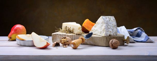 Cheese aged in hay, Mimolette cheese, Toma Brusca cheese with pears and walnuts on wooden table. - Photo, Image