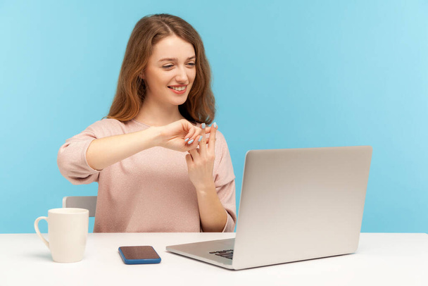 Positive manager, woman employee showing hashtag symbol while talking on video call with client, communicating online, planning web marketing strategy. indoor studio shot isolated on blue background - 写真・画像