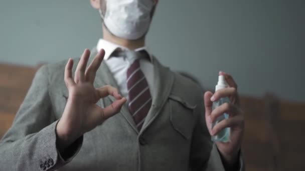 Freelancer standing in office with hand sanitizer in hands and showing OK sign saying everything is fine. Handsome man protect his hands using sanitizer. Quarantine work concept. Prores 422 - Video