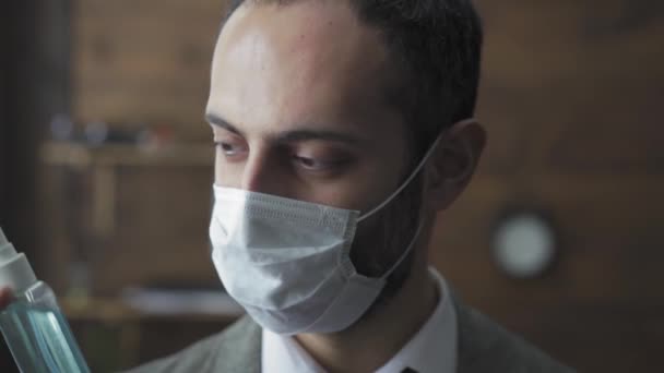 Freelancer in protective mask showing hand sanitizer standing in the modern office. Handsome man protect his hands using sanitizer. Quarantine work concept. Prores 422 - Video