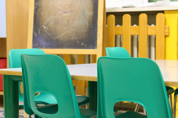 intérieur d'une salle de classe à l'école primaire sans enfants avec de petites chaises en plastique vert et le tableau noir sur le fond
 - Photo, image