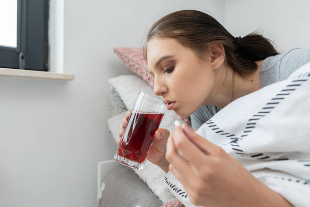 Hot tea with herbs. A young teenage girl lies sick from her bed. Acute cold. - Fotografie, Obrázek