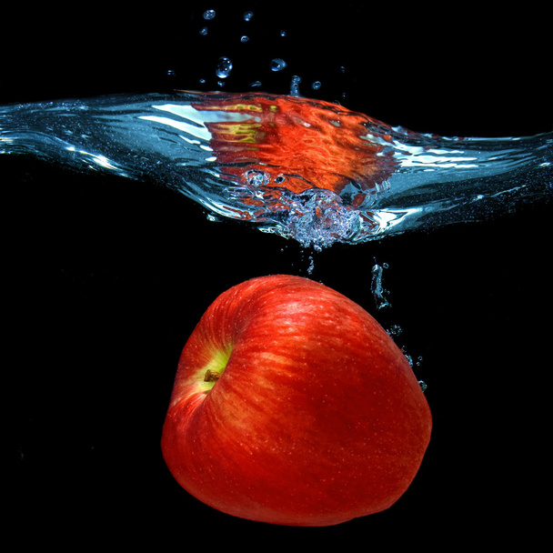 Red apple dropped into water with splash isolated on black - Photo, image