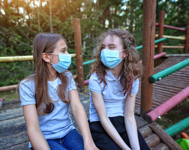 Jóvenes amigas se ríen y hablan durante la plaga del coronavirus afuera - Foto, Imagen